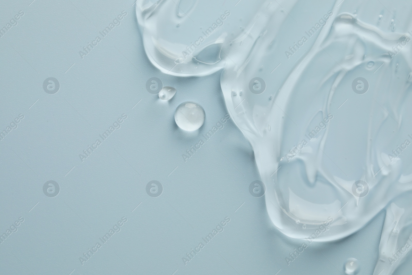 Photo of Clear cosmetic gel on light blue background, top view. Space for text