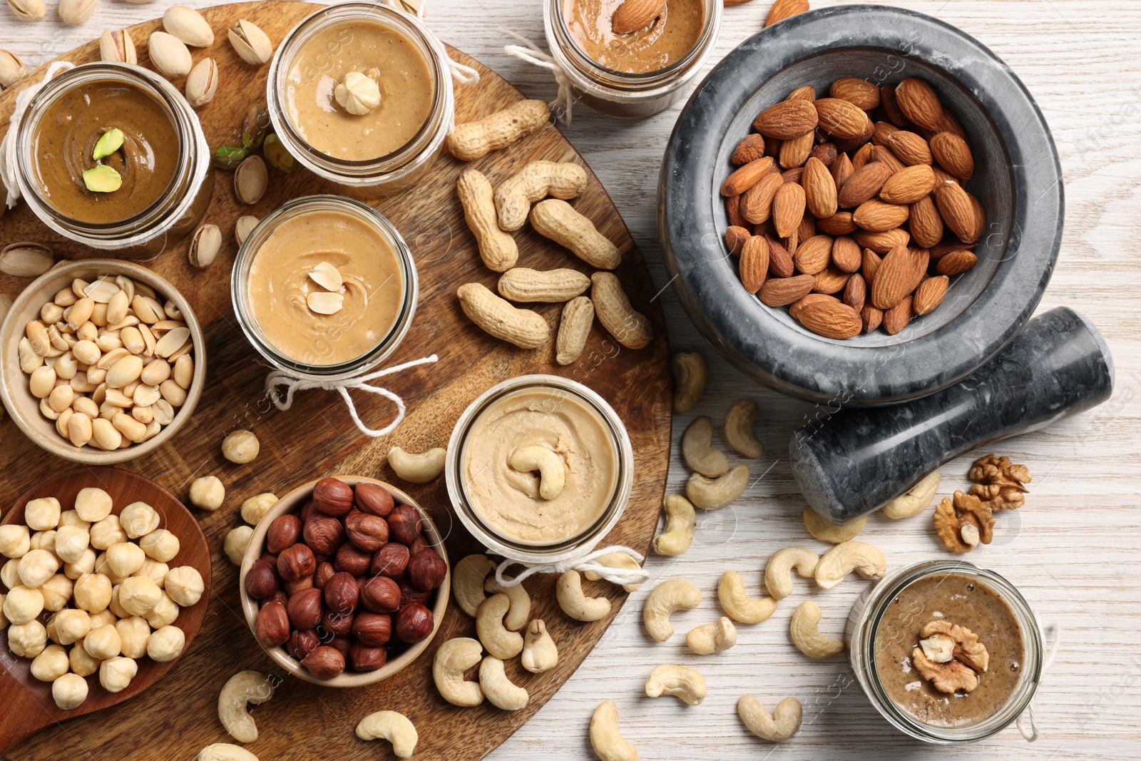 Photo of Making nut butters from different nuts. Flat lay composition on wooden table