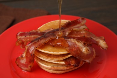 Pouring delicious pancakes with bacon at table, closeup