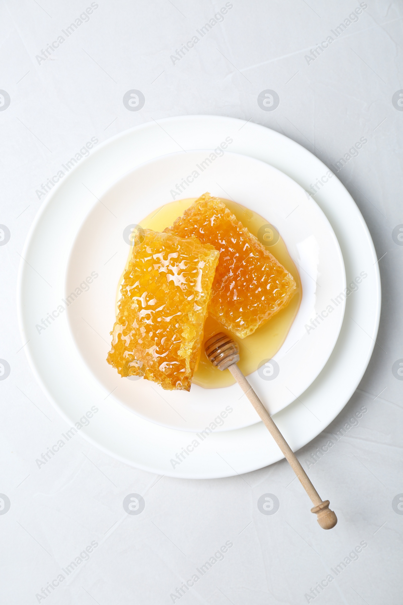 Photo of Natural honeycombs with tasty honey and dipper on white table, top view