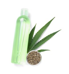 Photo of Bottle of hemp cosmetics with green leaf and seeds isolated on white, top view