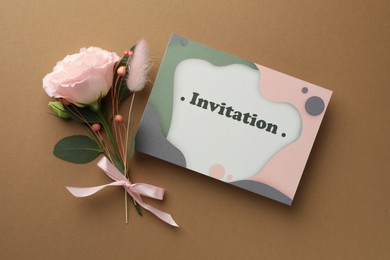 Card with word Invitation and beautiful flowers on beige background, flat lay