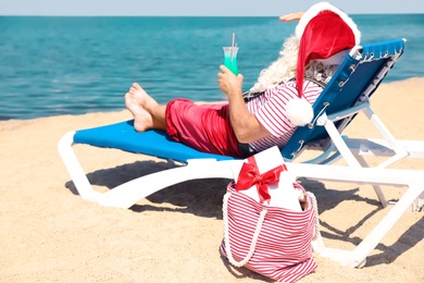 Authentic Santa Claus with cocktail resting on lounge chair at resort