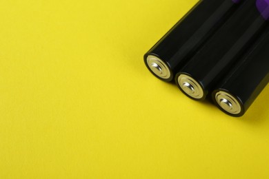 New AAA batteries on yellow background, closeup. Space for text