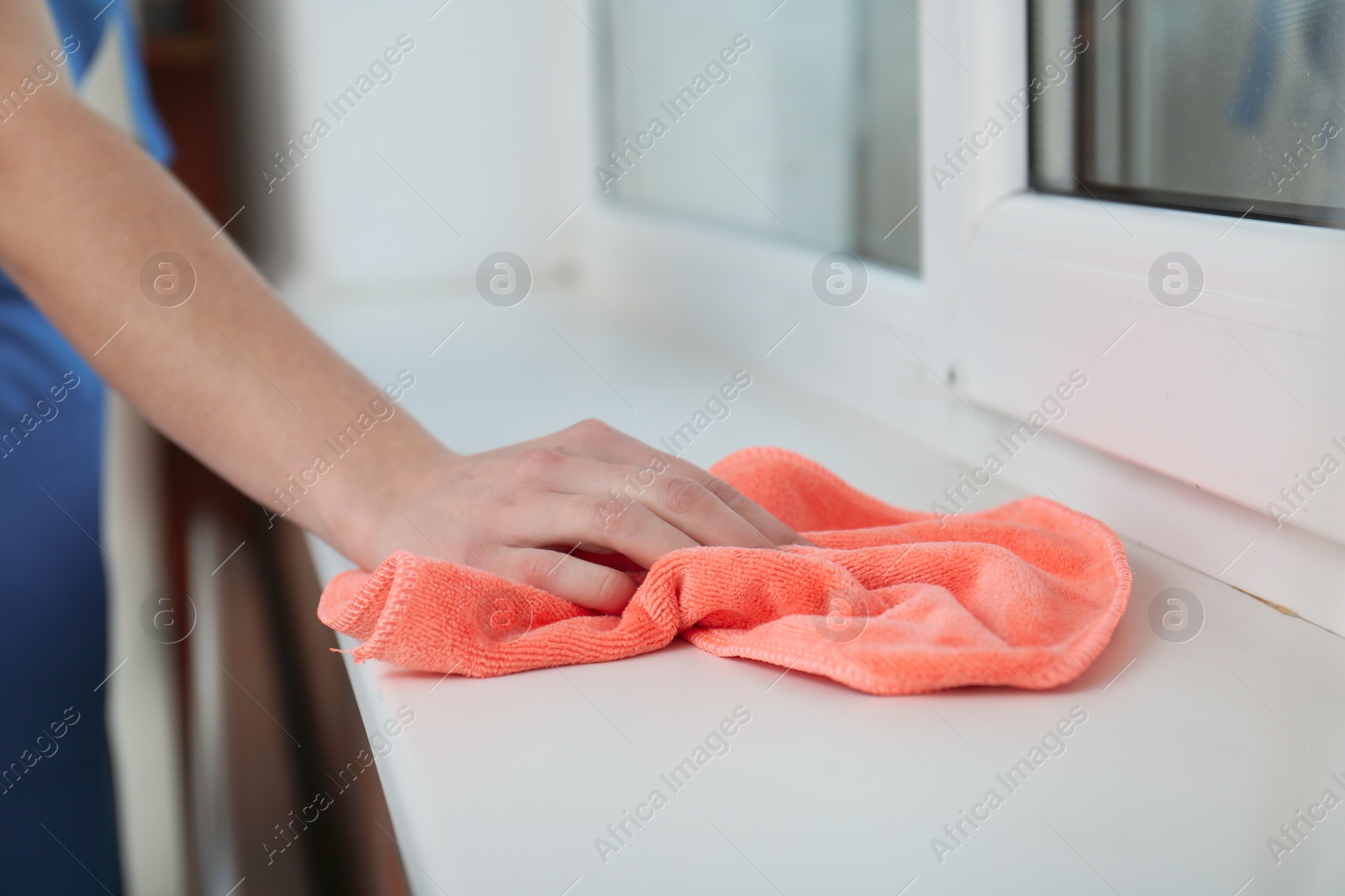 Photo of Woman cleaning window sill with cloth, closeup