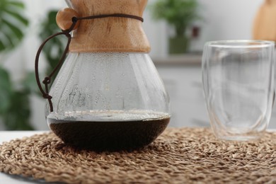 Photo of Chemex coffeemaker with coffee and glass on table, closeup