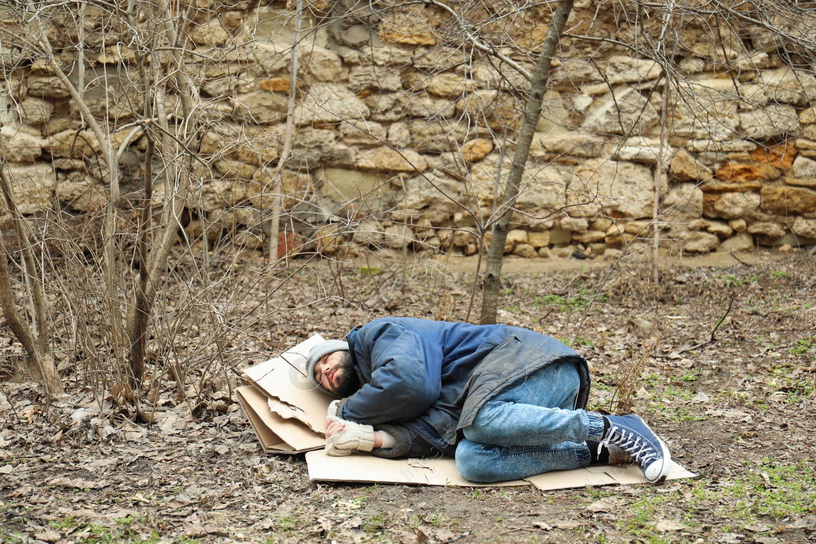 Photo of Poor homeless man lying on ground in city park