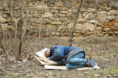 Photo of Poor homeless man lying on ground in city park