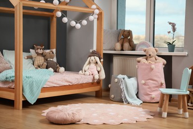 Photo of Stylish child room interior with wooden bed in shape of house and toys