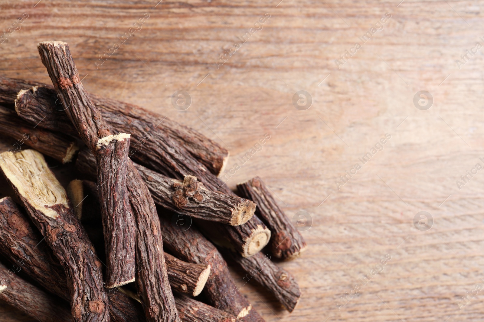 Photo of Dried sticks of liquorice root on wooden table, space for text