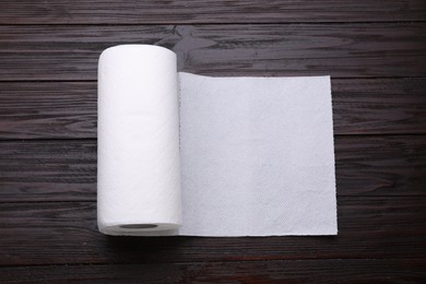 Photo of Roll of tissue towels on wooden table, top view