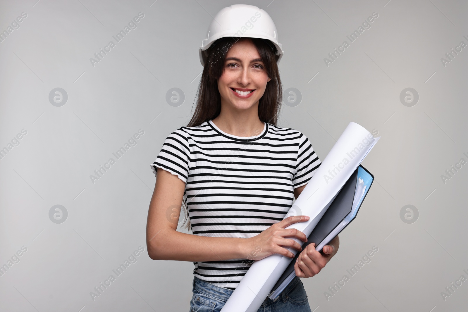 Photo of Architect in hard hat with draft and folder on light grey background