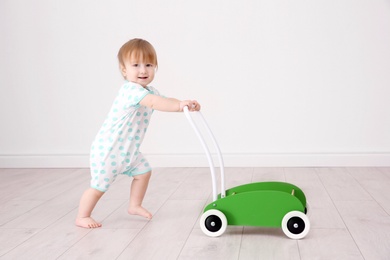 Photo of Cute baby playing with toy walker, indoors