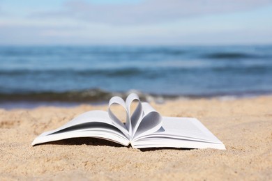 Open book on sandy beach near sea