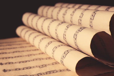 Old wrapped sheets with music notes on black background, closeup