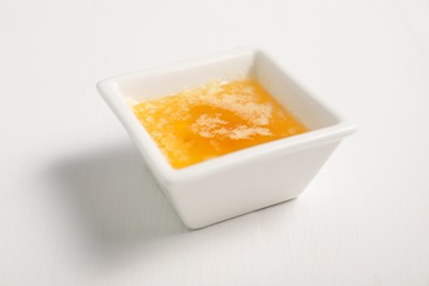 Photo of Melted butter in bowl on white wooden table, closeup