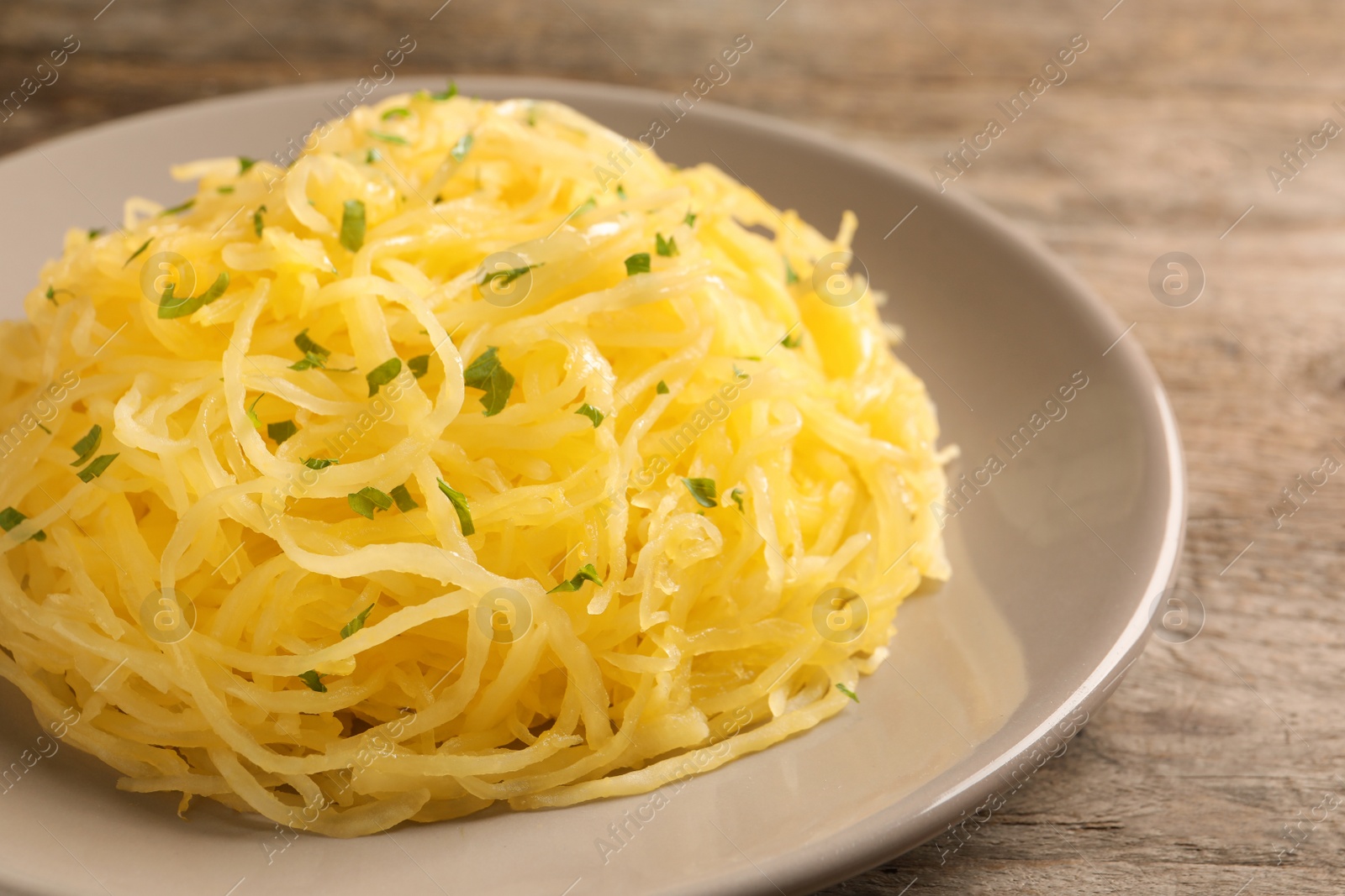 Photo of Plate with cooked spaghetti squash on wooden table