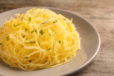Photo of Plate with cooked spaghetti squash on wooden table