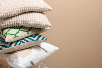 Photo of Stack of soft pillows on small table near beige wall. Space for text