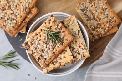 Photo of Cereal crackers with flax, sunflower, sesame seeds and rosemary on grey table, top view