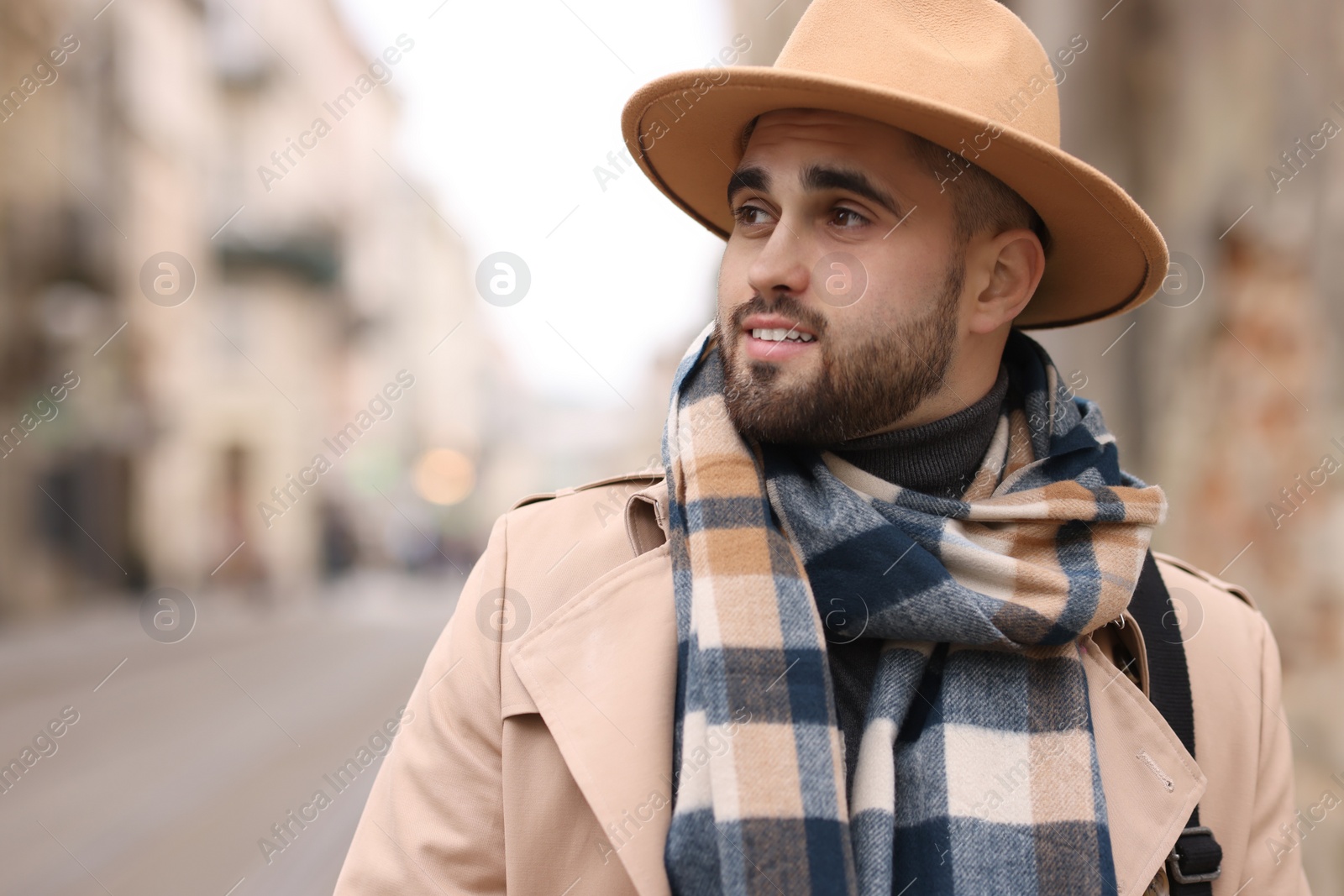 Photo of Handsome man in warm scarf outdoors. Space for text