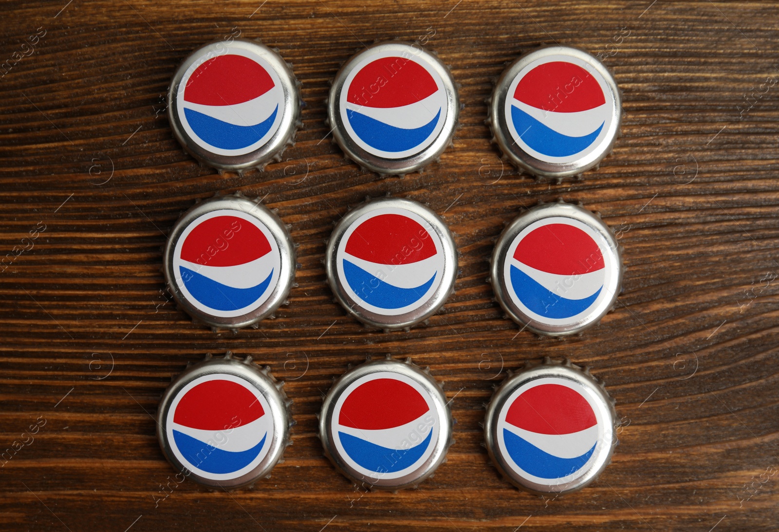 Photo of MYKOLAIV, UKRAINE - FEBRUARY 11, 2021: Pepsi lids on wooden background, flat lay