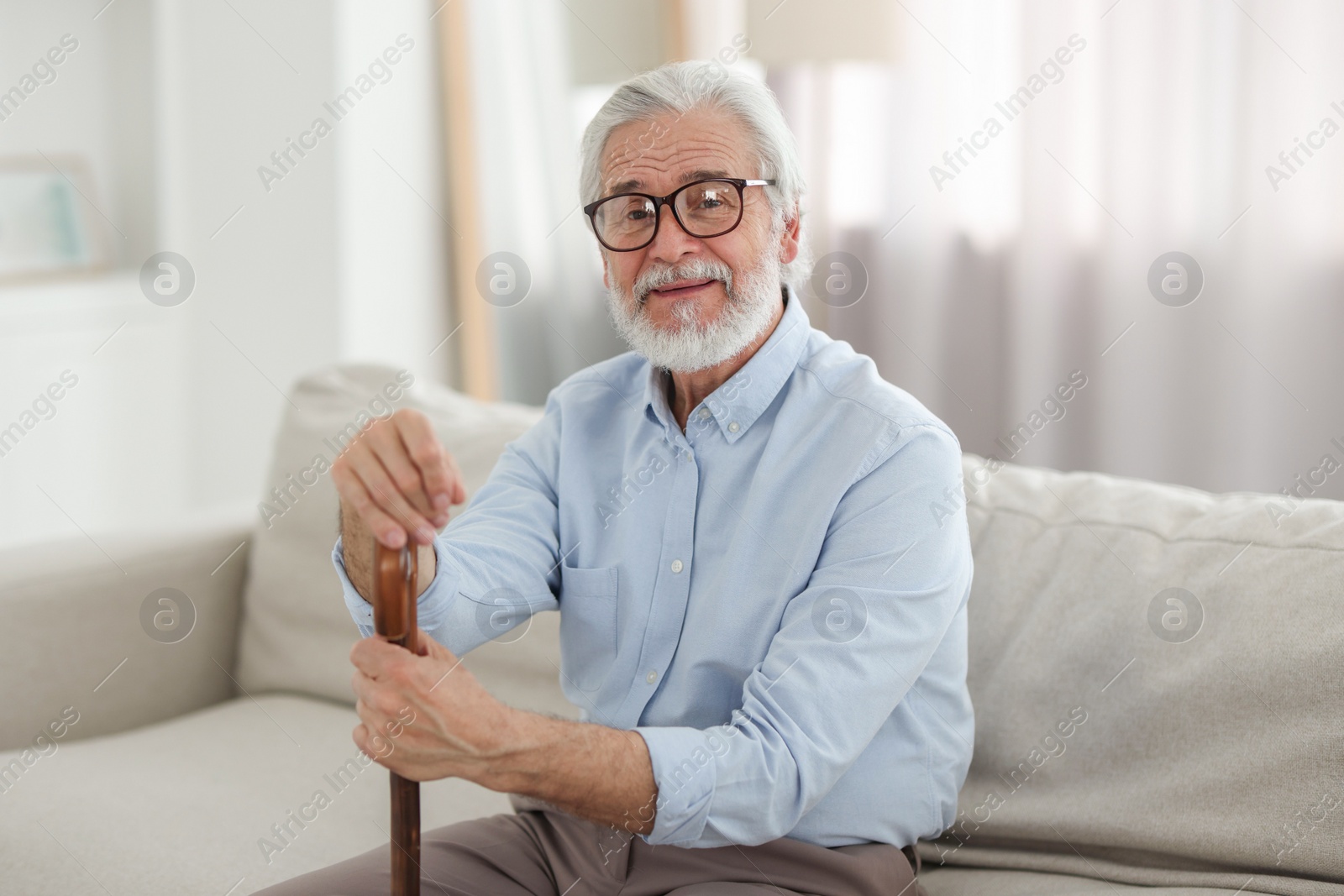 Photo of Portrait of grandpa with glasses and walking cane on sofa indoors