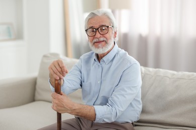 Photo of Portrait of grandpa with glasses and walking cane on sofa indoors