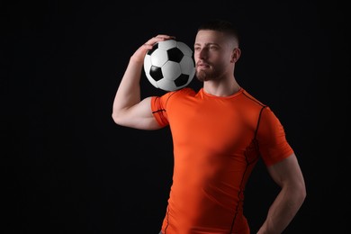 Photo of Athletic young man with soccer ball on black background