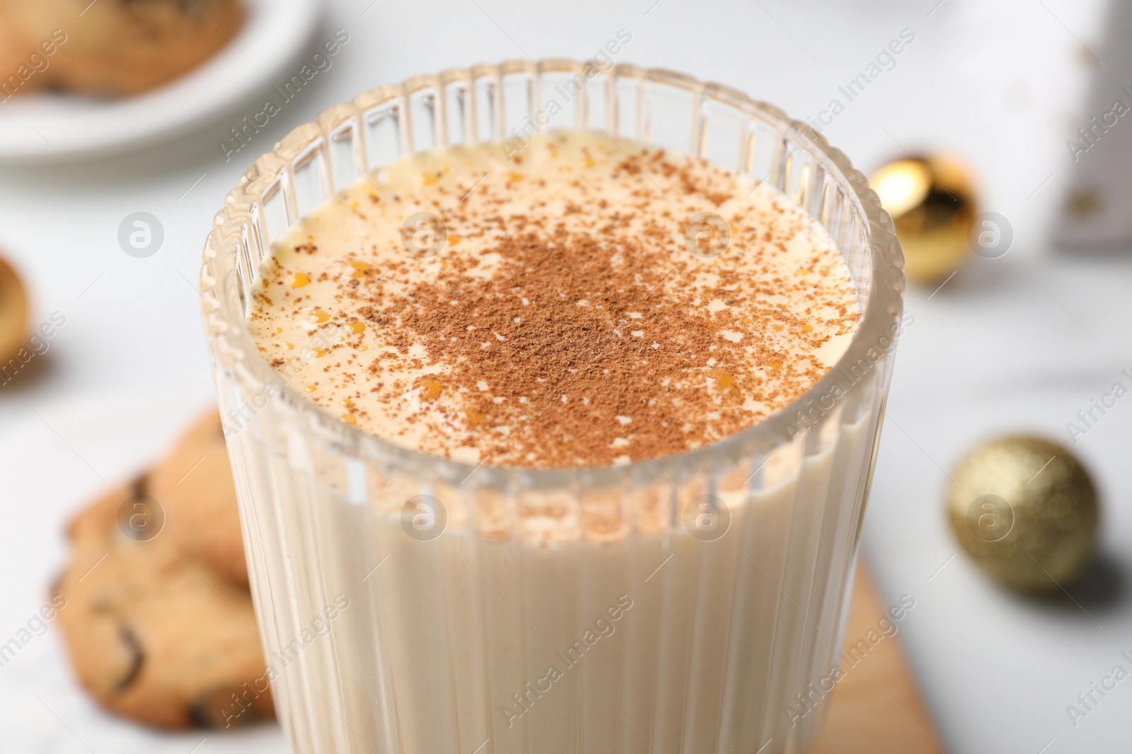 Photo of Glass of delicious eggnog with cinnamon on table, closeup