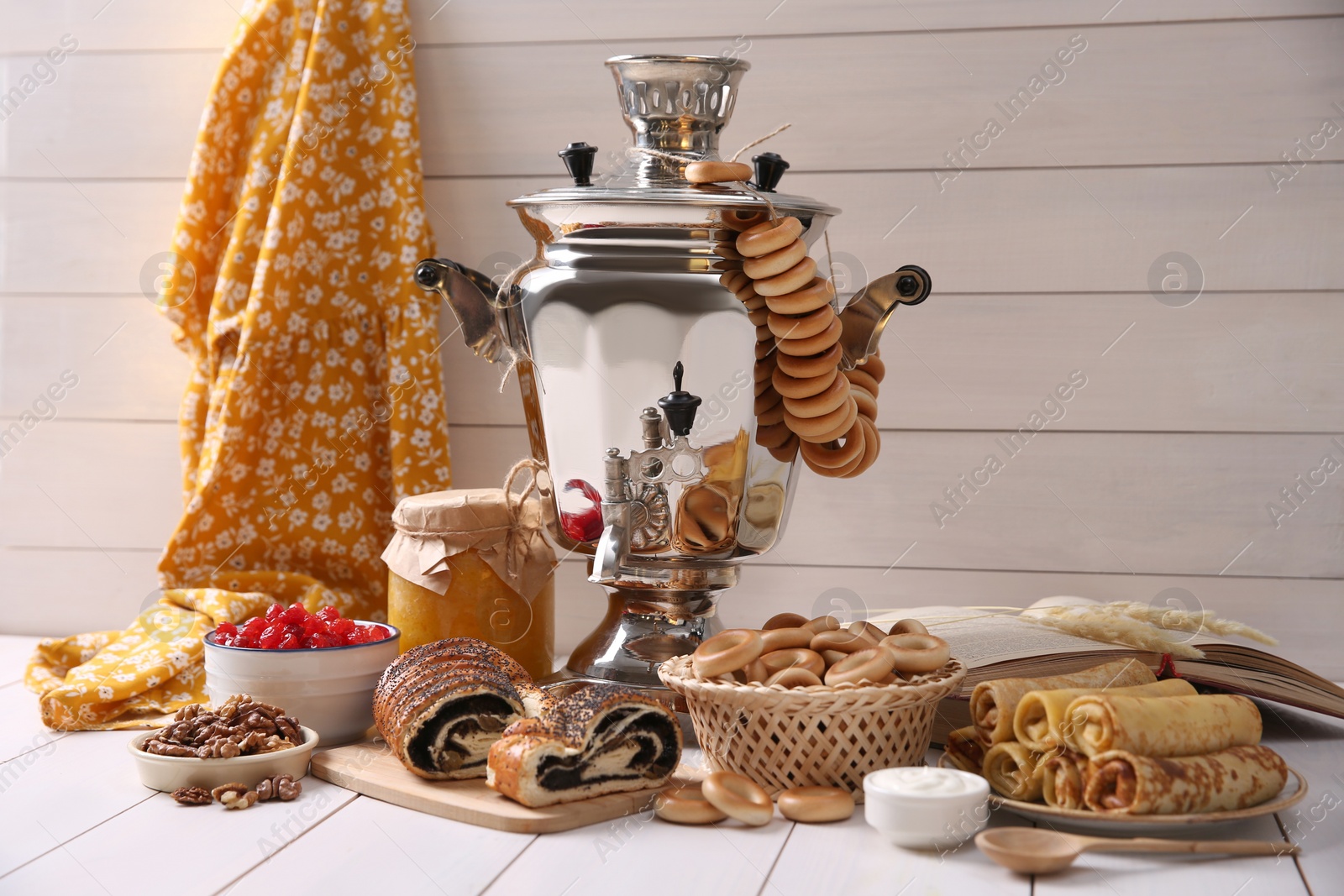 Photo of Traditional Russian samovar and treats on white wooden table