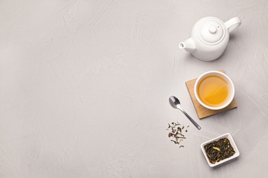 Flat lay composition with cup of hot aromatic tea on light grey table. Space for text