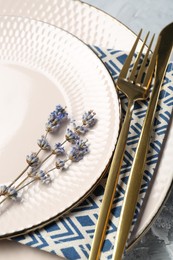 Clean plates, cutlery, napkin and lavender flowers on table, closeup