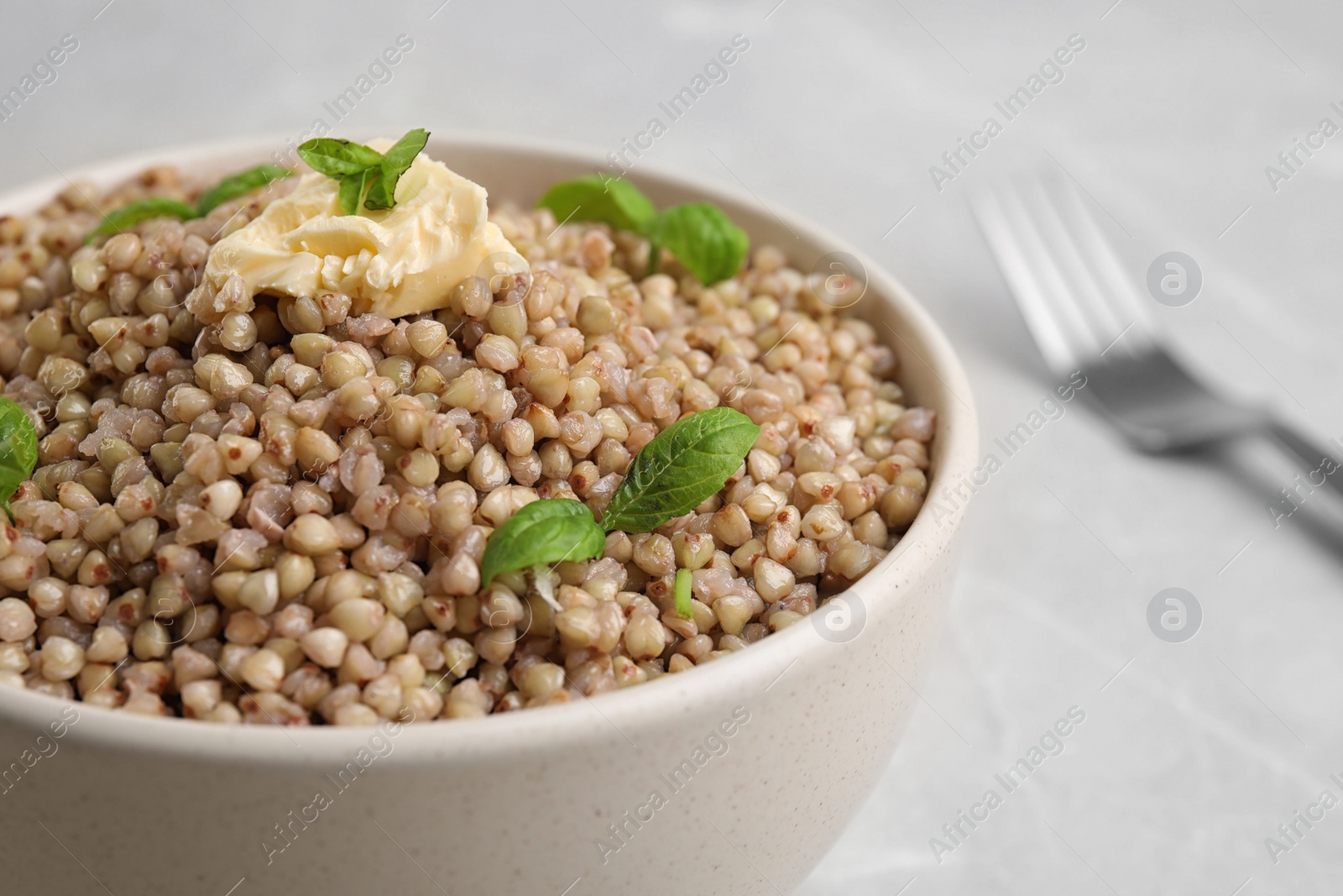 Photo of Tasty buckwheat porridge with butter on grey marble table, closeup