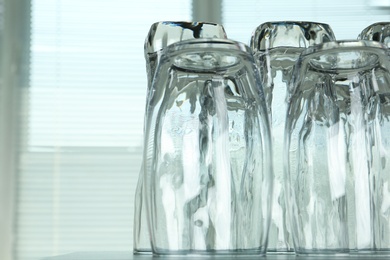Photo of Empty glasses on grey table against blurred background, closeup. Space for text