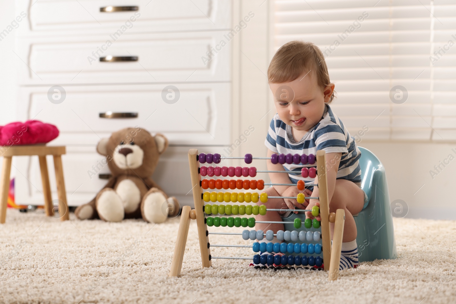 Photo of Little child with abacus sitting on plastic baby potty indoors. Space for text
