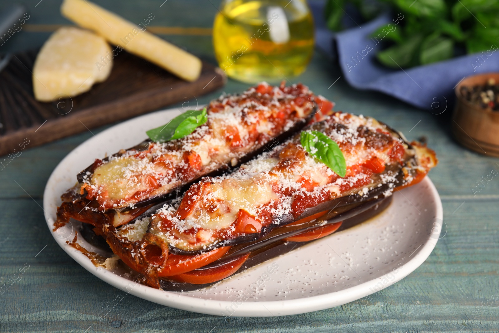 Photo of Baked eggplant with tomatoes, cheese and basil on blue wooden table