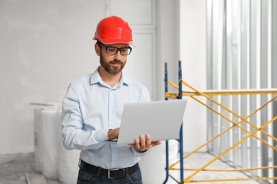 Photo of Professional engineer in hard hat with laptop indoors