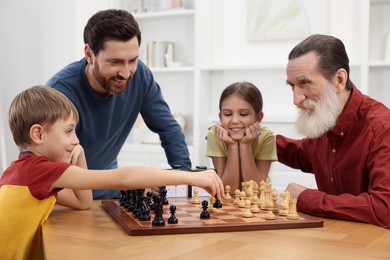 Family playing chess together at table in room