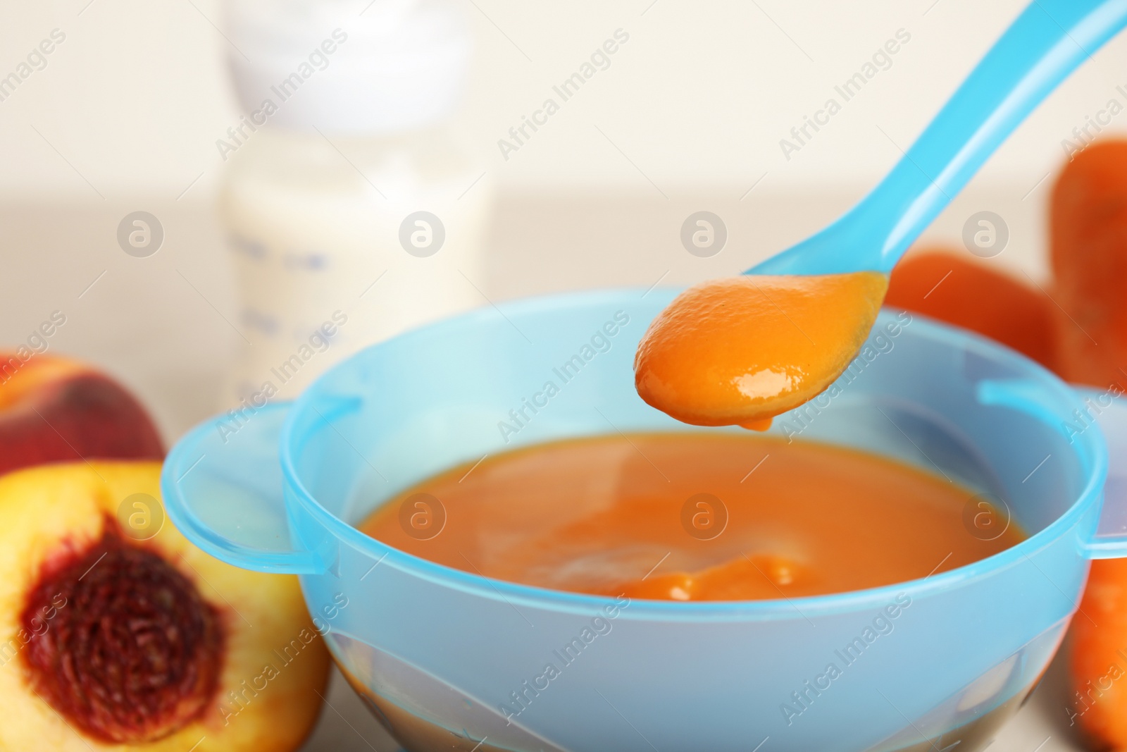 Photo of Baby food in bowl and fresh ingredients on table, closeup