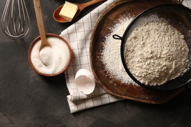 Photo of Making dough. Flour in sieve, sugar and butter on grey textured table, flat lay