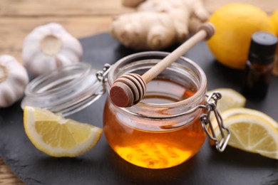 Cold remedies. Jar of honey and lemon on slate plate, closeup. Cough treatment