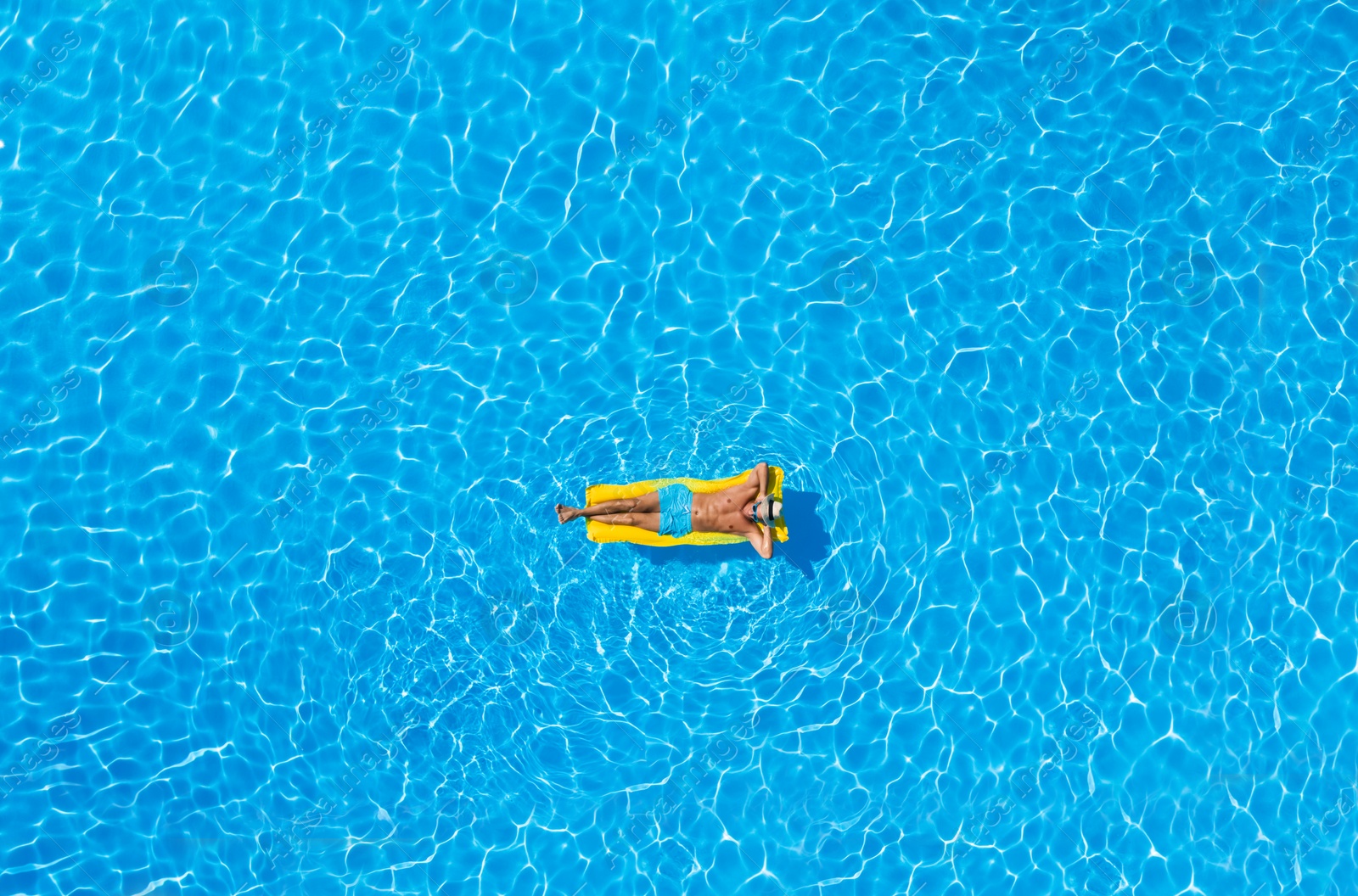 Image of Young man with inflatable mattress in swimming pool, top view. Summer vacation