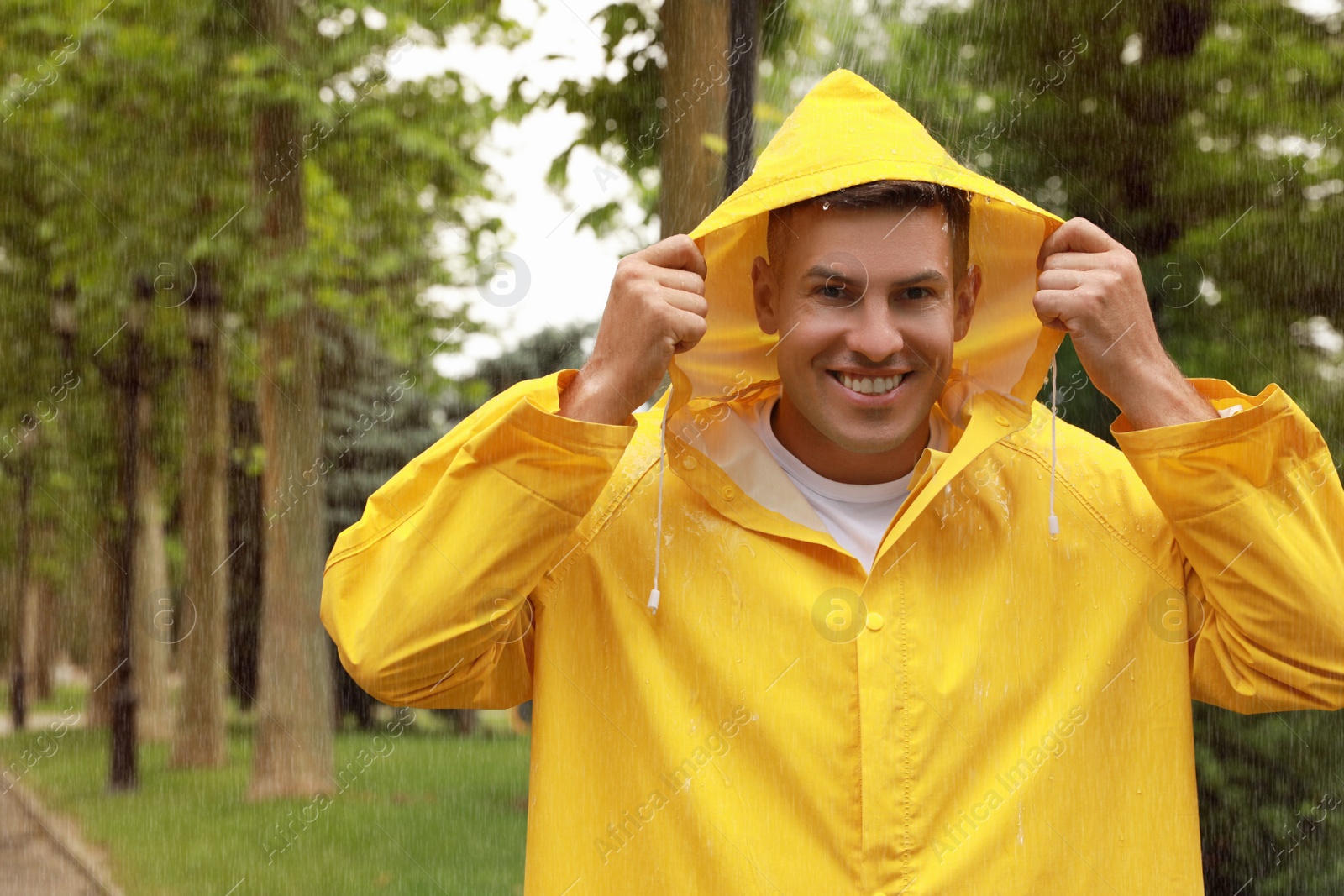 Photo of Man with raincoat walking under rain in park