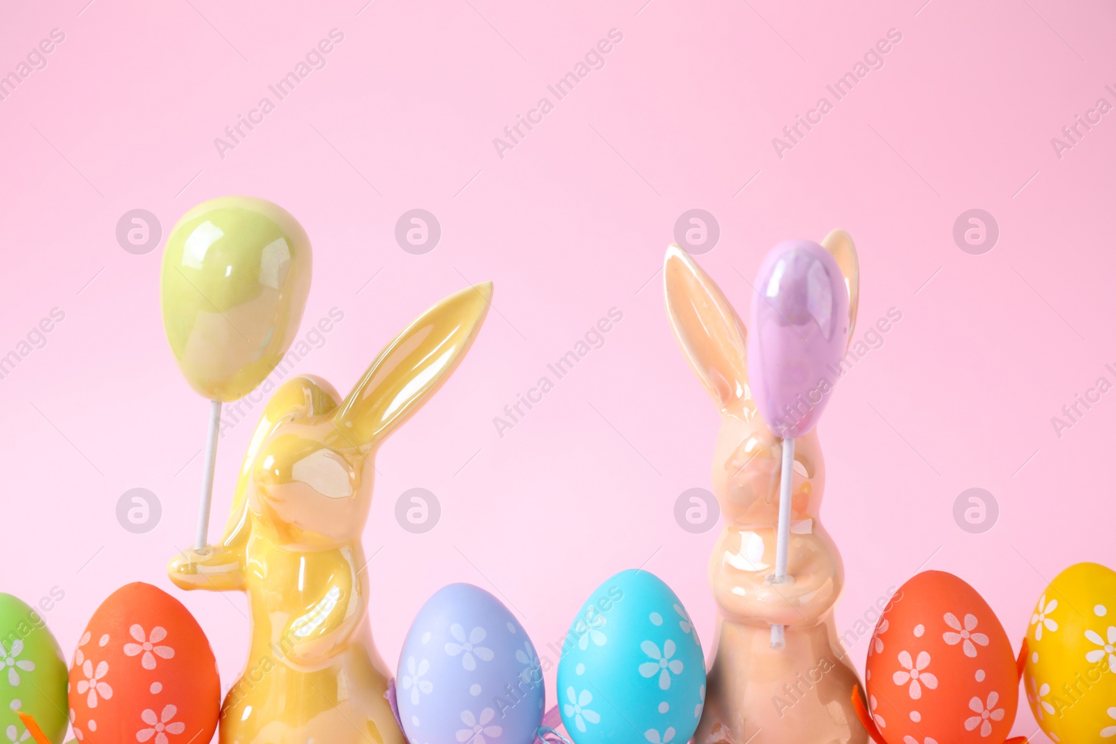 Photo of Easter bunnies and painted eggs on pink background