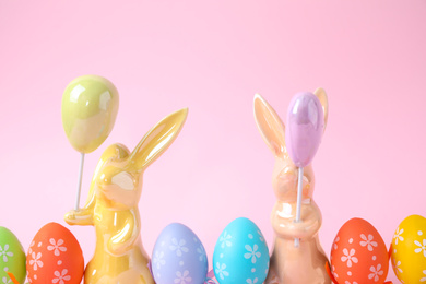 Photo of Easter bunnies and painted eggs on pink background