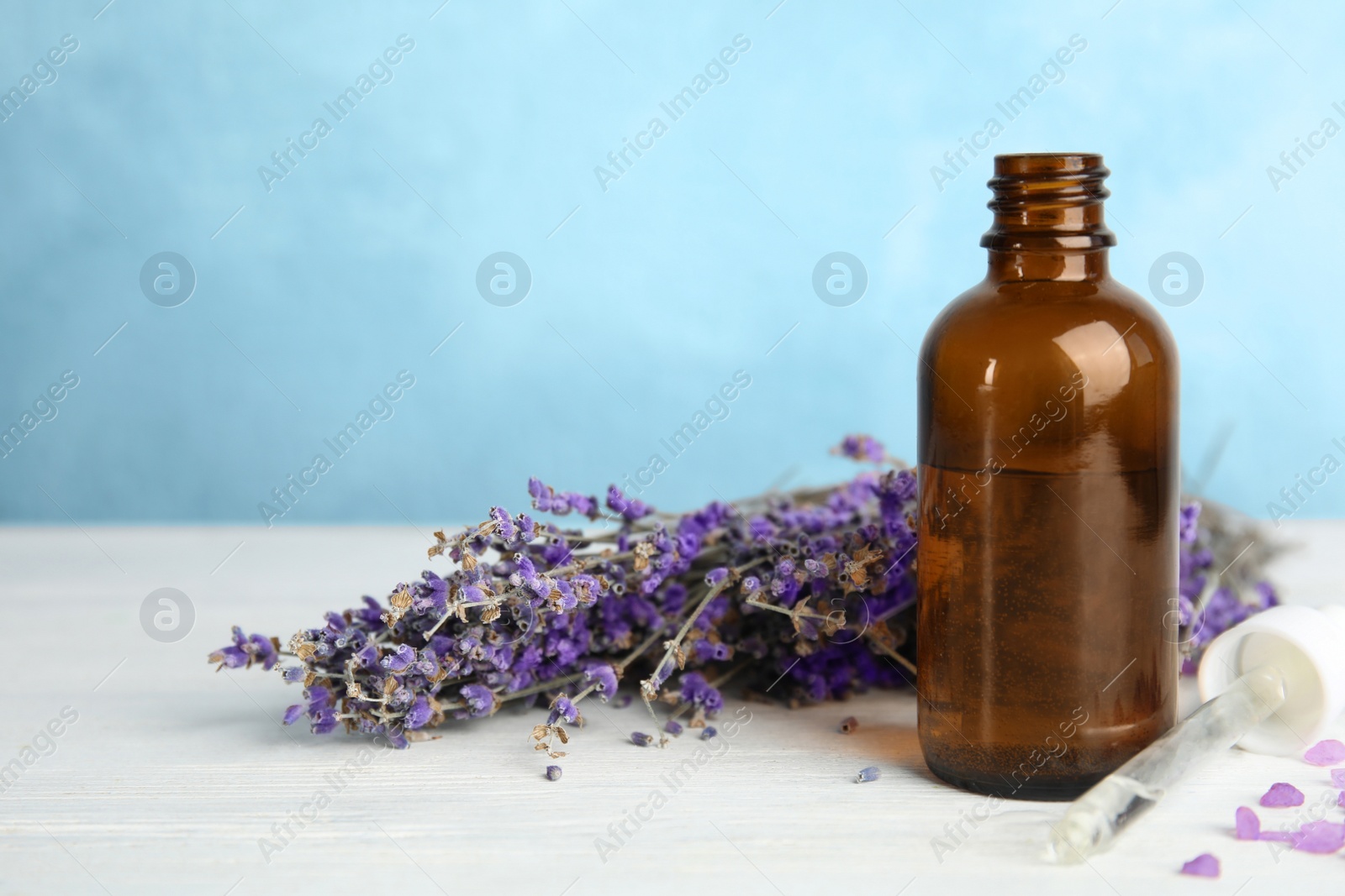 Photo of Bottle with aromatic lavender oil on wooden table. Space for text