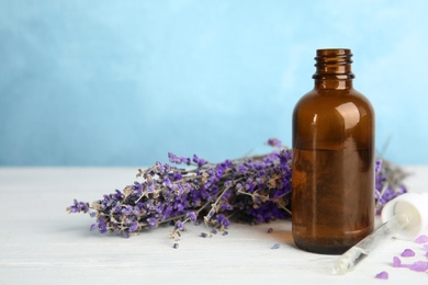 Bottle with aromatic lavender oil on wooden table. Space for text