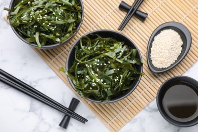 Fresh laminaria (kelp) seaweed served on white marble table, flat lay