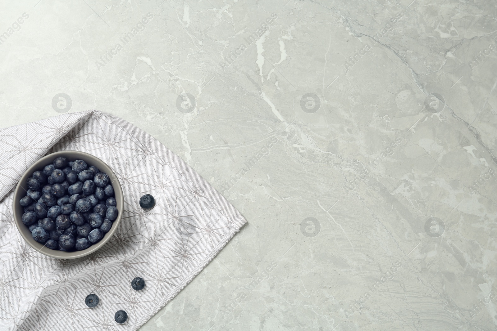 Photo of Ceramic bowl with blueberries on grey table, flat lay  and space for text. Cooking utensil